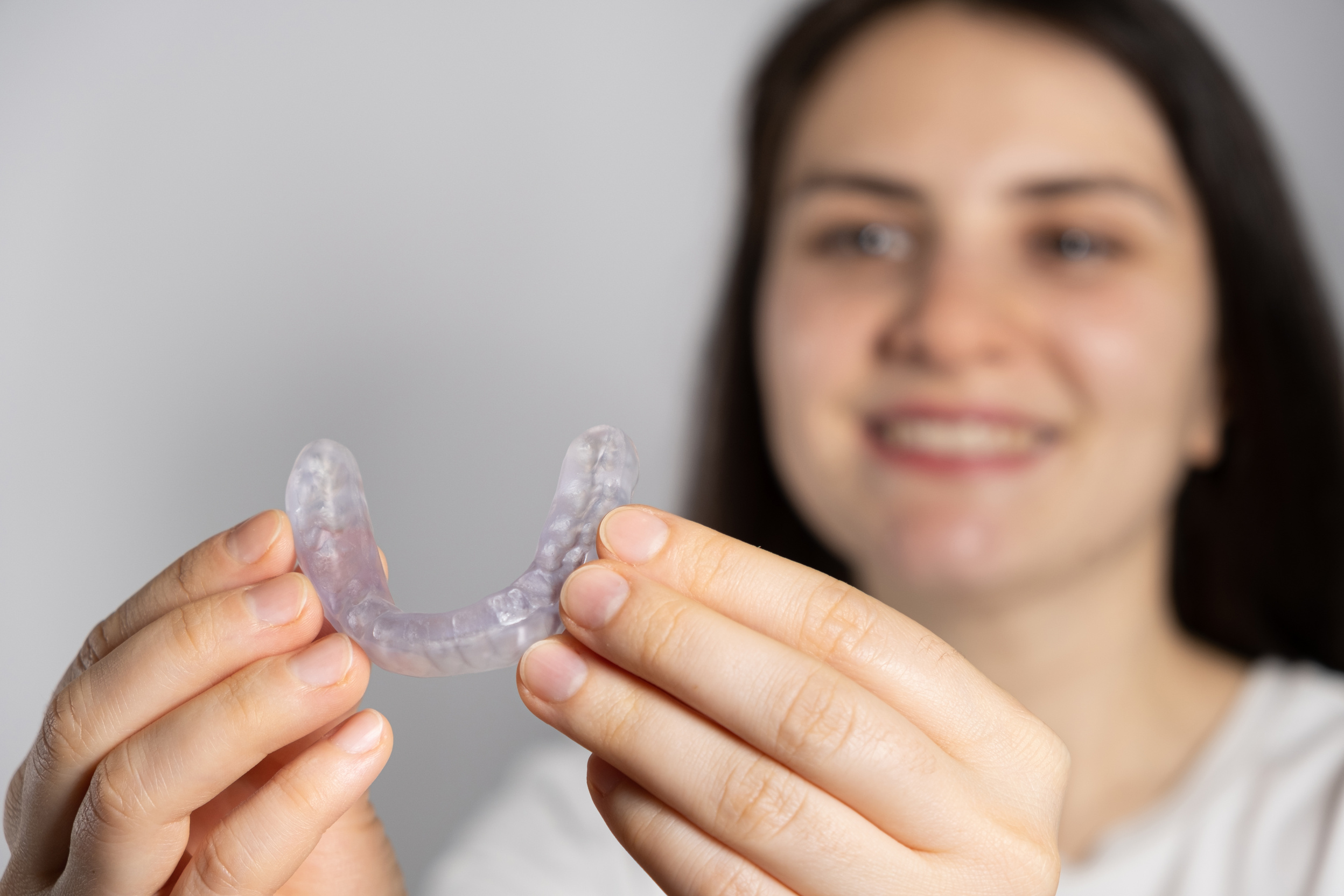 A woman holds dental mouthguard, splint for the treatment of dysfunction of the temporomandibular joints, bruxism, malocclusion, to relax the muscles of the jaw.